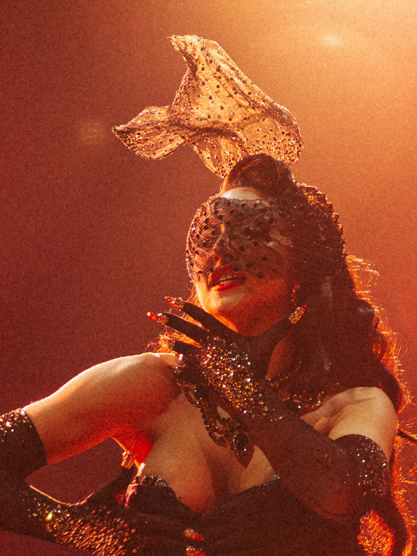 A masked burlesque performer poses during a variety and cabaret show