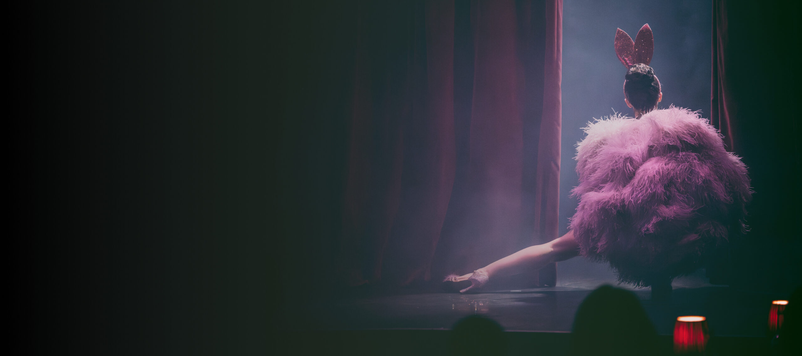 A burlesque performer appearing from the curtain