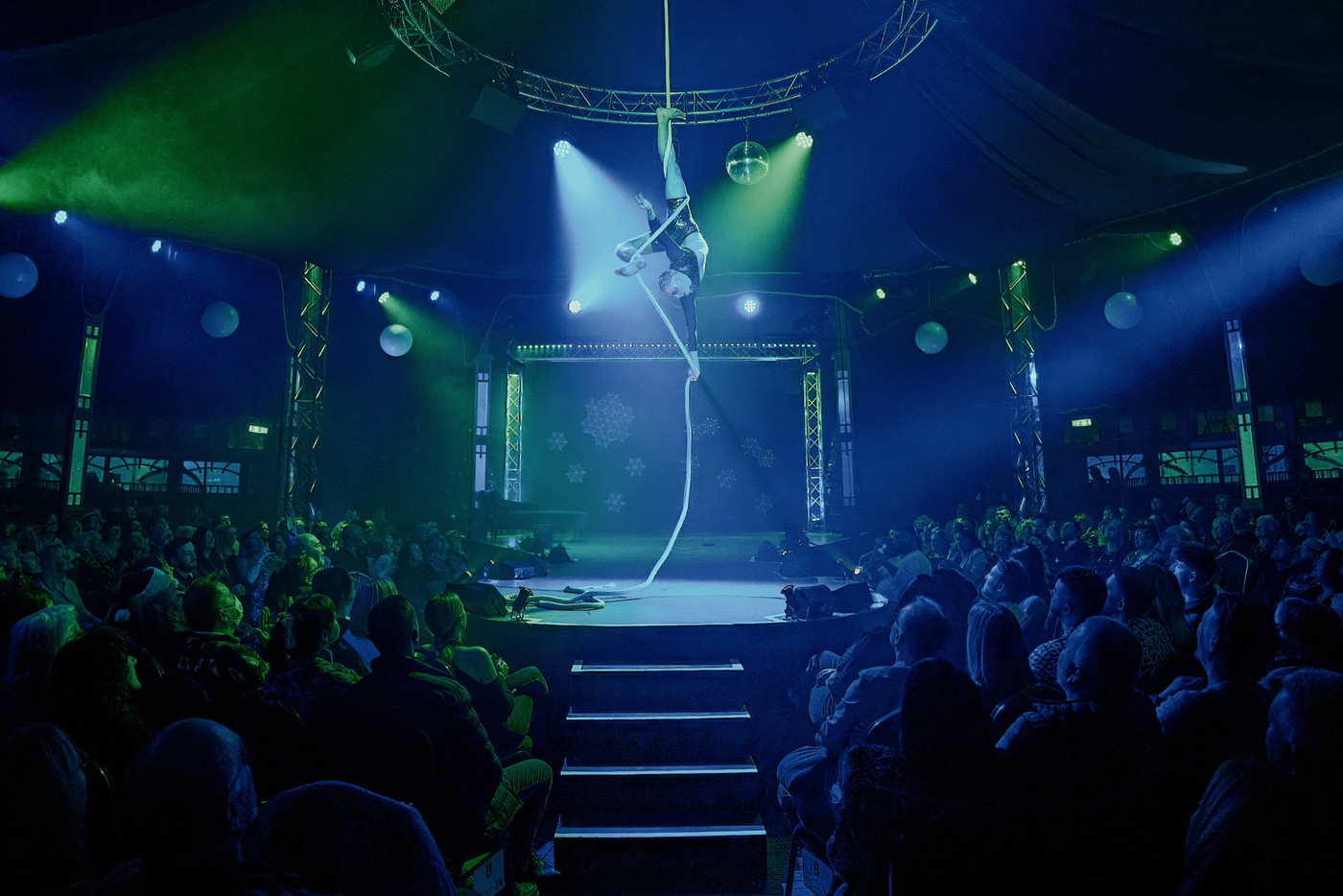 Aerial artist performing centre stage in a spiegeltent while an eager audience looks on