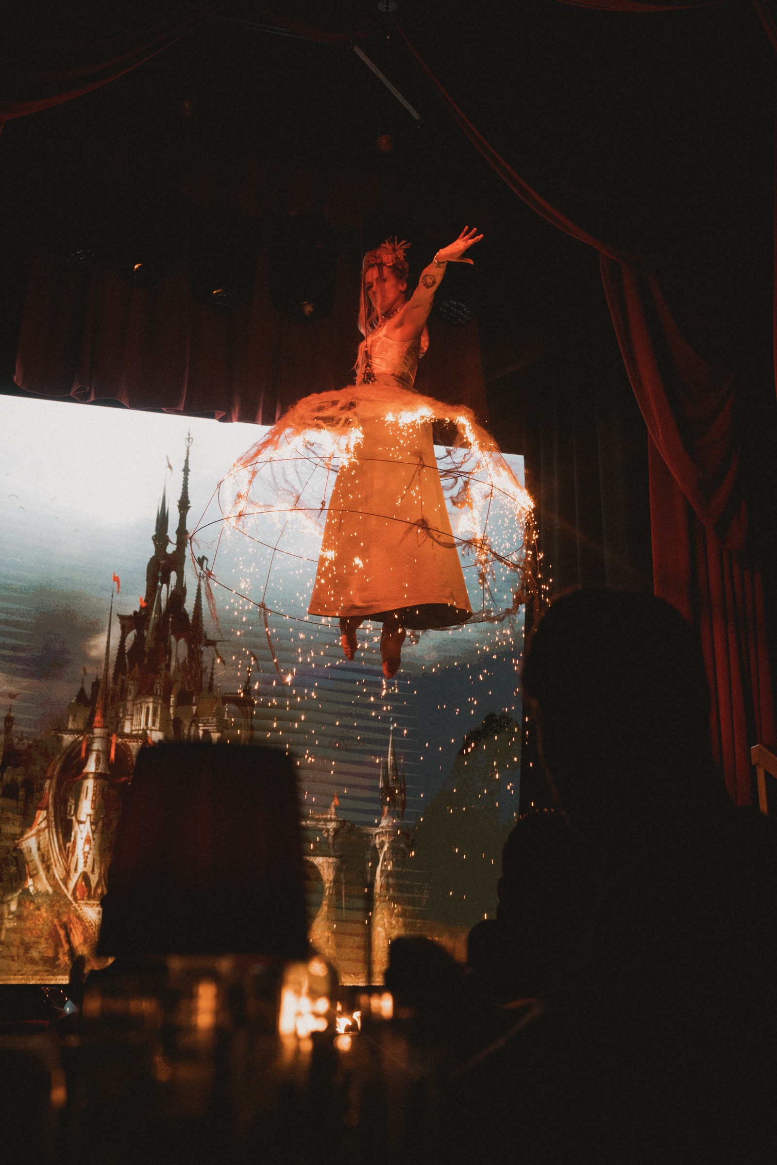 A dramatic shot of an aerialist wearing a dress that is set on fire during an event for London Fashion Week