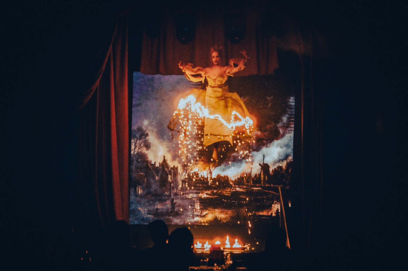 A dramatic shot of an aerialist wearing a dress that is set on fire during an event for London Fashion Week