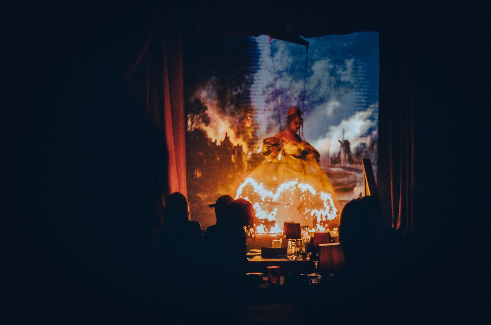 A dramatic shot of an aerialist wearing a dress that is set on fire during an event for London Fashion Week
