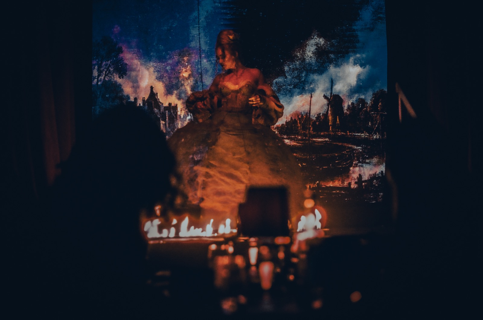 A dramatic shot of an aerialist wearing a dress that is set on fire during an event for London Fashion Week