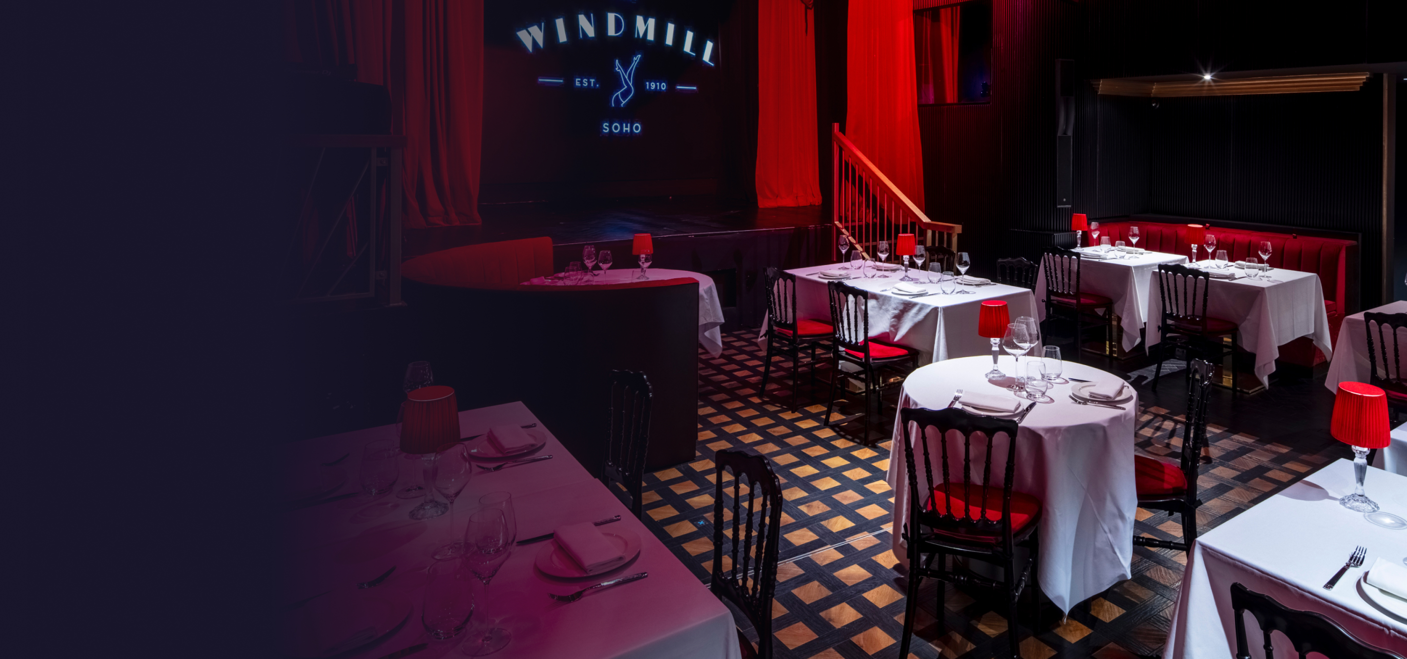 Restaurant venue with tables set out and a stage in the background