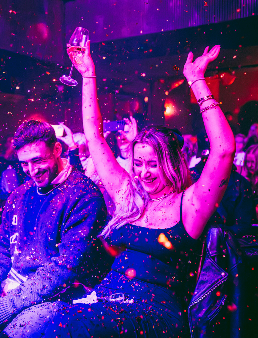 Guests showered in confetti and raising their hands with excitement at a party event